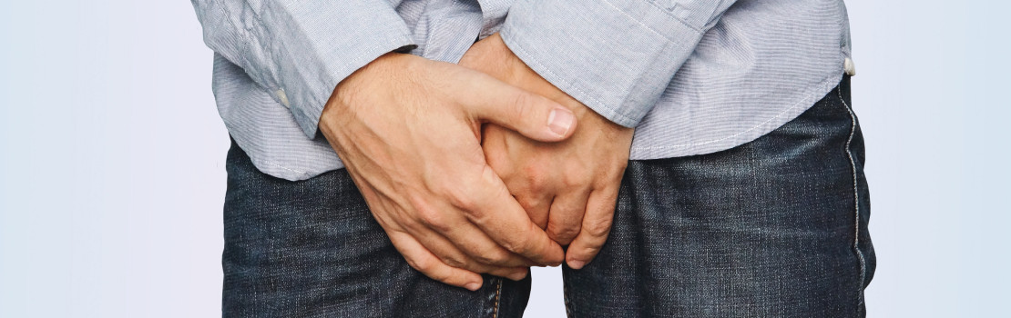 Zrelý muž s rukou na podbrušku, prejav príznakov zväčšenej prostaty