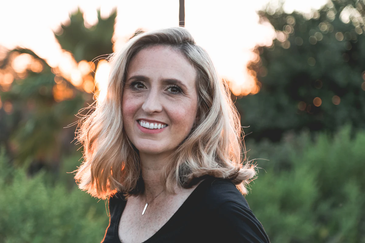 Žena okolo 40 s blond vlasmi, pokojný úsmev vonku